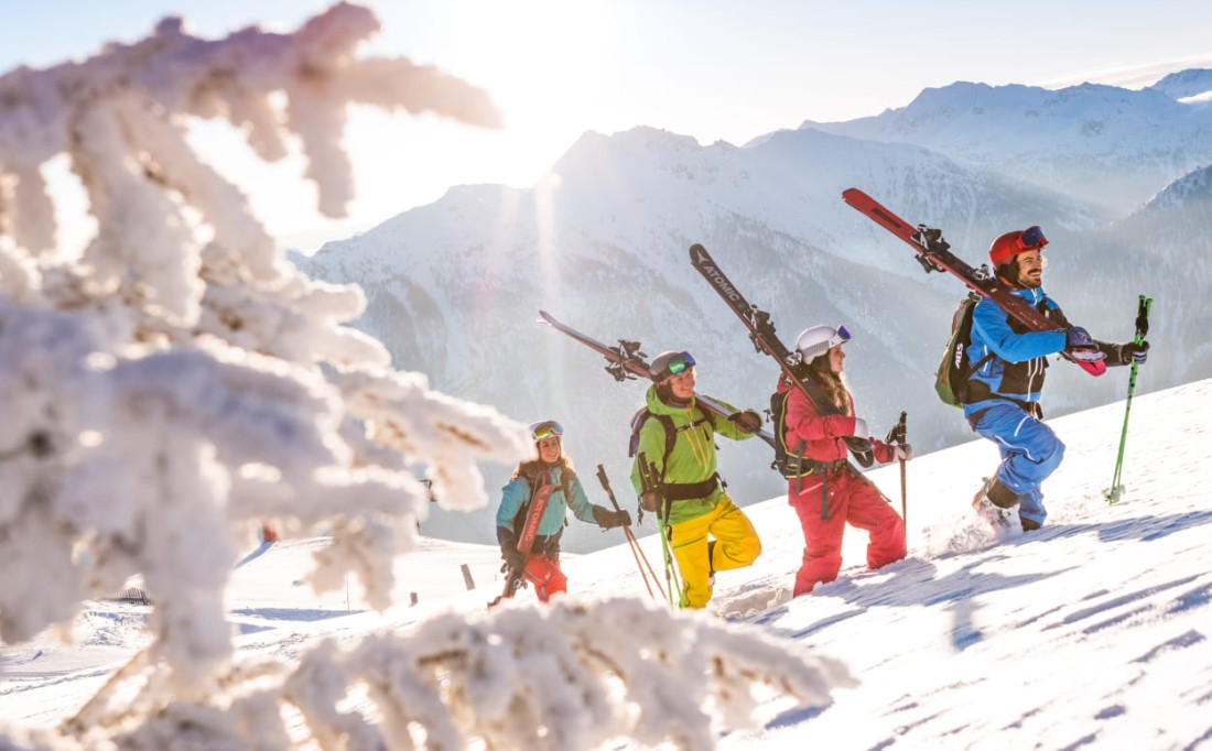 Skifahrer stapfen mit geschulterten Skiern durch den Schnee © Flachau Tourismus