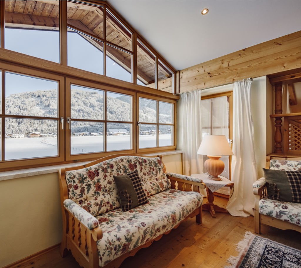 Wohnbereich mit großes Fensterfront und Blick in die verschneiten Berge von Flachau 